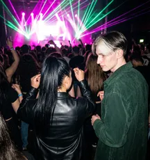 Twee vrienden op de dansvloer, met groene lasers boven de menigte.